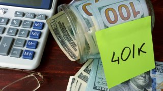 Calculadora junto a dinero en efectivo y sticker que dice 401K, una cuenta de ahorros para el retiro