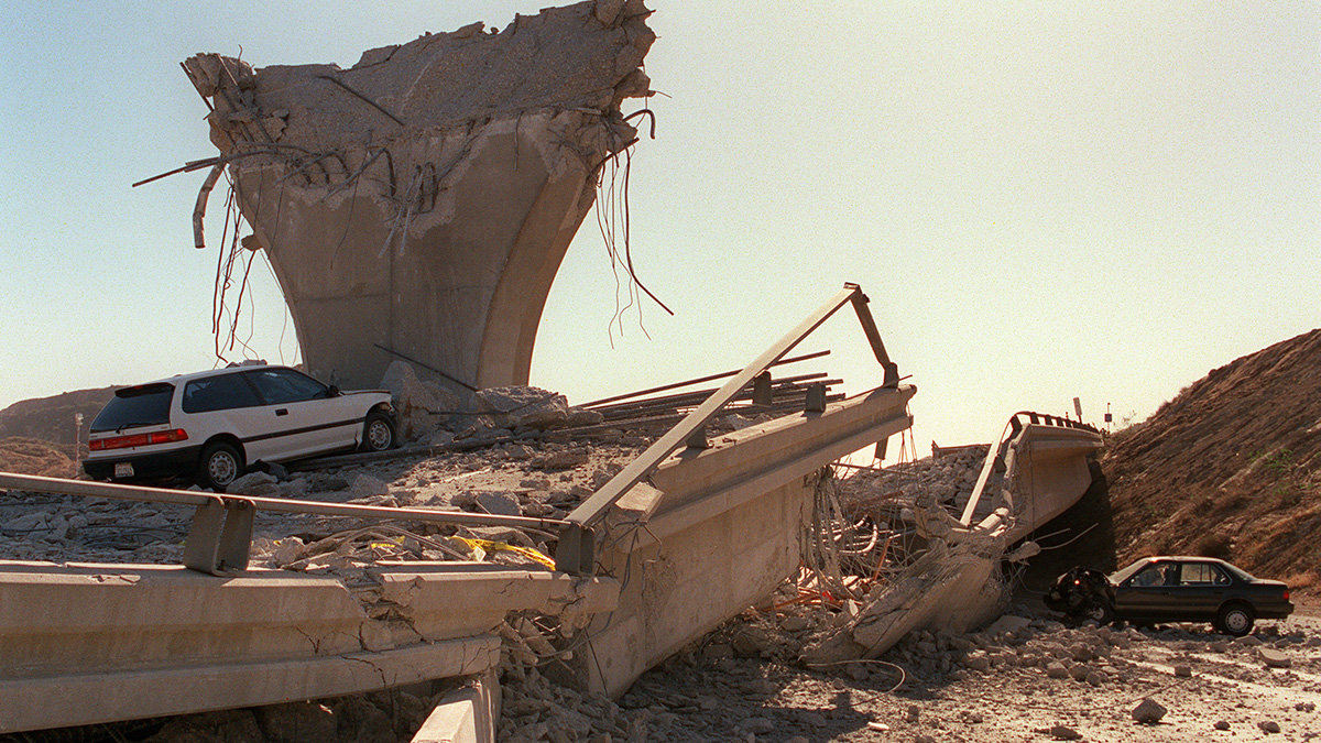 Autos destrozados debajo del conector colapsado de la Interestatal 5 pocas horas después del terremoto de Northridge, el 17 de enero de 1994, en Sylmar, California. El terremoto a las 4:31 a.m., hora estándar del Pacífico en Reseda, un vecindario en la ciudad de Los Ángeles, California. (JONATHAN NOUROK / AFP / Getty Images)