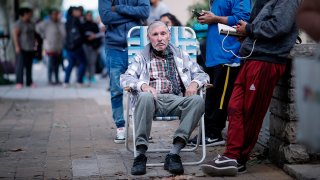 Adultos mayores esperan en fila para poder cobrar su jubilación en un Banco de San Justo, en la provincia de Buenos Aires.