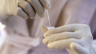 A health worker dressed in personal protective equipment conducts a test.