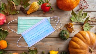 Protective mask and thanksgiving pumpkins against wooden background