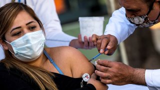 Un trabajador sanitario aplica una vacuna en el brazo a una mujer en Monterrey, Nuevo León