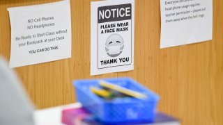 West Lawn, PA - October 22: A sign in a classroom that reads "Notice, please wear a face mask. Thank you" next to signs about rules of cell phone usage in class. At Wilson High School in West Lawn, PA Thursday afternoon October 22, 2020 where the school has been taking precautions for students doing in person school to prevent the spread of Coronavirus / COVID-19.
