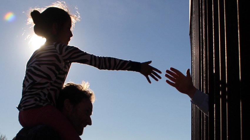 A girl from Anapra, a neighbourhood on the outskirts of Ciudad Juarez in Mexico, touches hands with a person on the United States through the border fence, during a prayer with priests and bishops from both countries to ask for the migrants and people of the area, on February 26, 2019. – Built two years ago, the Anapra fence is one of several reinforced border barriers that the administration of US President Donald Trump calls the first sections of the wall. (Photo by Herika MARTINEZ / AFP)        (Photo credit should read HERIKA MARTINEZ/AFP via Getty Images)