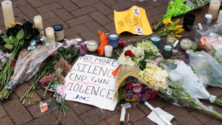 Signs and flowers are pictured at a makeshift memorial for victims of the 4th of July mass shooting in downtown Highland Park, Illinois on July 6, 2022.