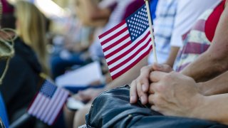 Hand holding a small American flag during a patriotic presentation for Veteran's Day.