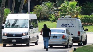 Foto de un agente armando corriendo entre vehículos forenses.