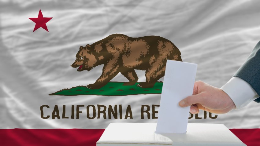 man putting ballot in a box during elections  in front of flag american state of california