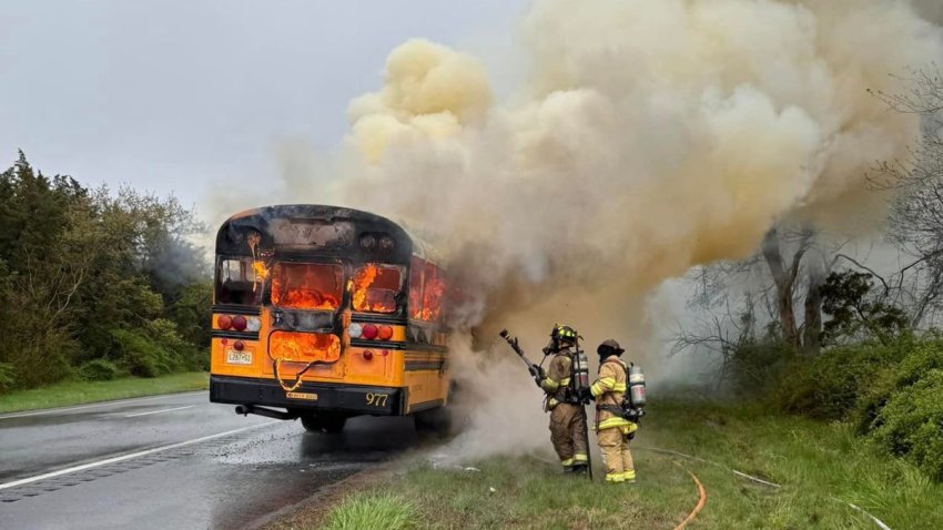 Firefighters working next to a burning school bus