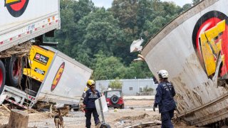 Miembros del Grupo de Trabajo de Búsqueda y Rescate Urbano de FEMA con un perro de búsqueda buscan en un área dañada por las inundaciones a lo largo del río Swannanoa en Asheville, Carolina del Norte, el 4 de octubre después del huracán Helene.