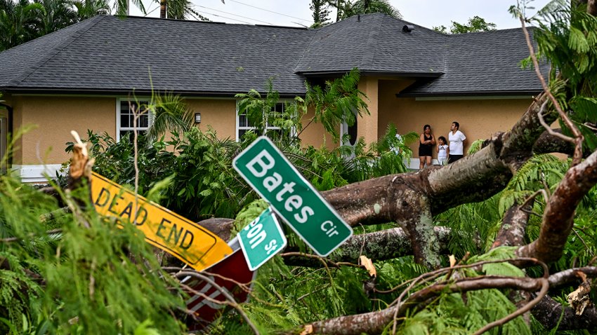 TOPSHOT – Oscar Garcia (R) with his family stands outside his house after getting hit by a reported tornado in Fort Myers, Florida, on October 9, 2024, as Hurricane Milton approaches. Florida residents fled or just hunkered down in the final hours October 9 before Milton pummels the state, as government emergency relief efforts were dragged to the center of the US election. (Photo by CHANDAN KHANNA / AFP) (Photo by CHANDAN KHANNA/AFP via Getty Images)