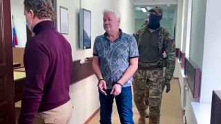 ARCHIVO - En esta imagen tomada de un video publicado por la Corte de Distrito de Lefortovo, Robert Shonov, ciudadano ruso que trabajó más de 25 años en el ahora clausurado consulado de Estados Unidos en Vladivostok, es escoltado por funcionarios a la sala en la Corte de Distrito de Lefortovo en Moscú, Rusia, el jueves 18 de mayo de 2023.