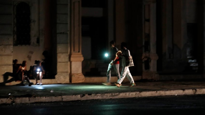 Personas caminan por una calle sin iluminación auxiliándose con la luz de su celular durante un apagón, el 18 de agosto de 2022, en La Habana (Cuba). EFE/Ernesto Mastrascusa