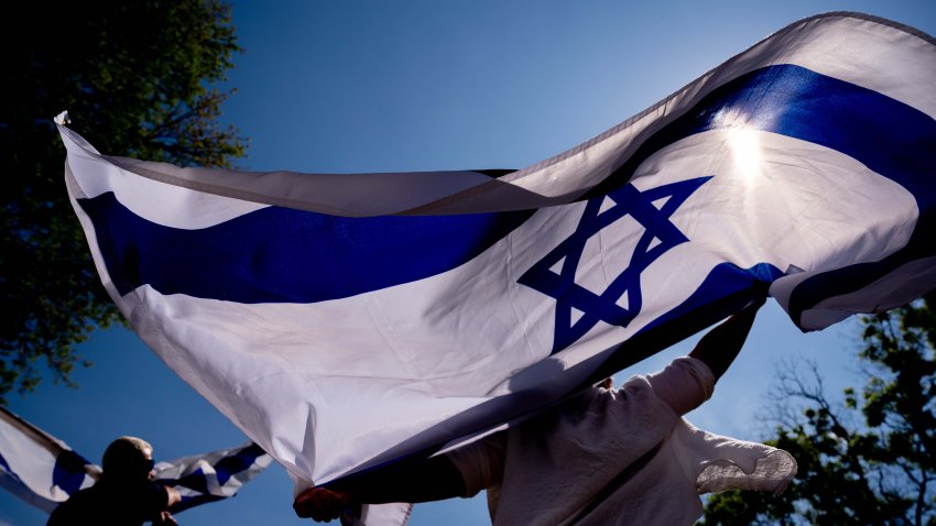 WASHINGTON, DC – MAY 2: Michal Rokah of Falls Church, Virginia (C) and Israeli Matan Showstack of Washington, DC (L) dance and wave large Israeli flags during a rally against campus antisemitism at George Washington University on May 2, 2024 in Washington, DC. A pro-Palestinian rally was also held at the school today, as protestors at college campuses around the country call for schools to divest from Israeli interests amid the ongoing war in Gaza. (Photo by Andrew Harnik/Getty Images)