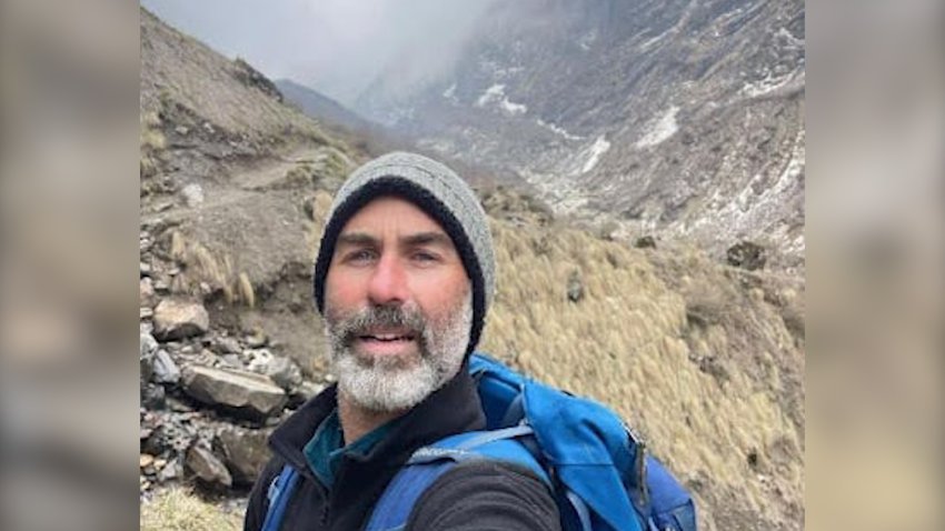 A photo of a man in a grey beanie hiking on a mountain